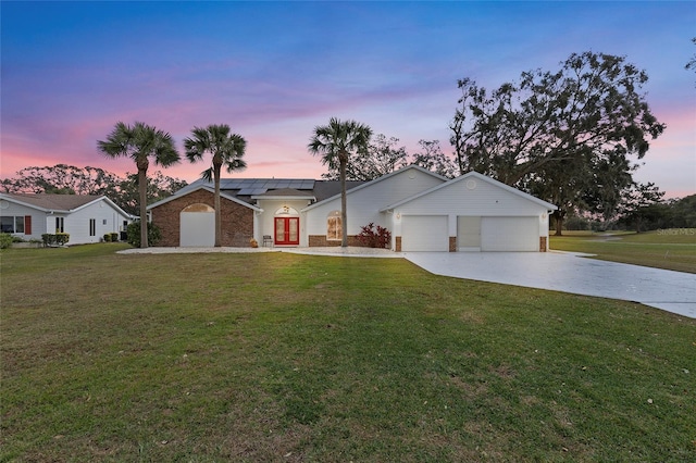 single story home featuring solar panels, a yard, and a garage