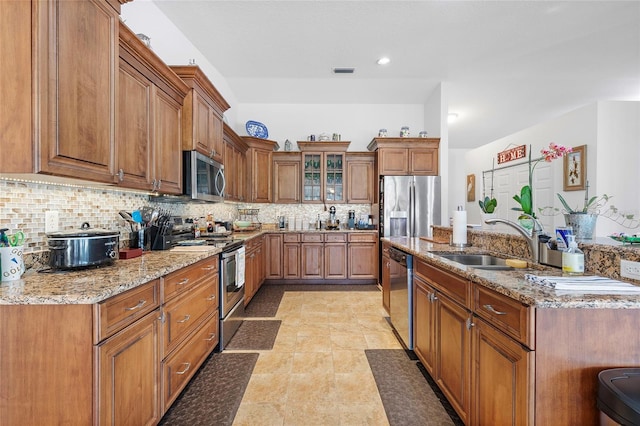 kitchen with decorative backsplash, appliances with stainless steel finishes, light stone counters, sink, and light tile patterned floors