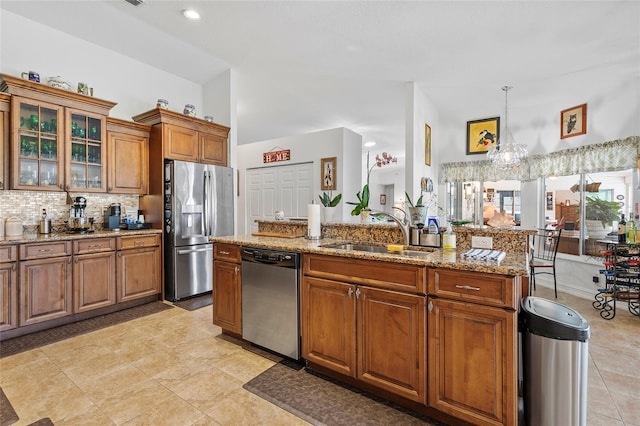 kitchen featuring light stone countertops, sink, hanging light fixtures, tasteful backsplash, and appliances with stainless steel finishes