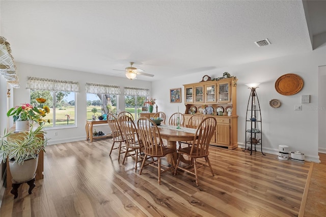 dining room with a textured ceiling, light wood-type flooring, and ceiling fan