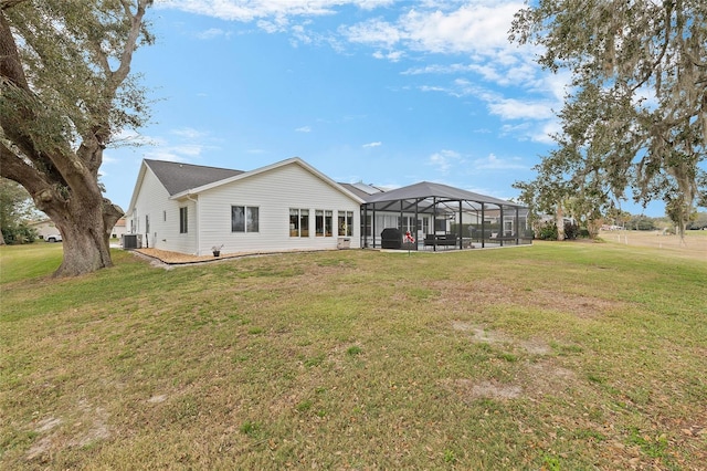 back of house featuring central AC, a yard, and glass enclosure