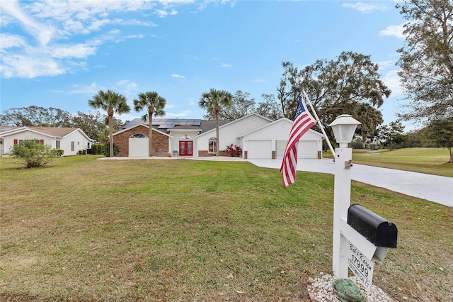 single story home featuring solar panels, a garage, and a front lawn