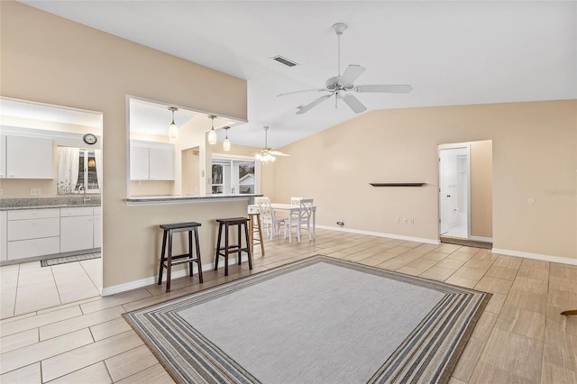 living room featuring ceiling fan, sink, light tile patterned floors, and lofted ceiling