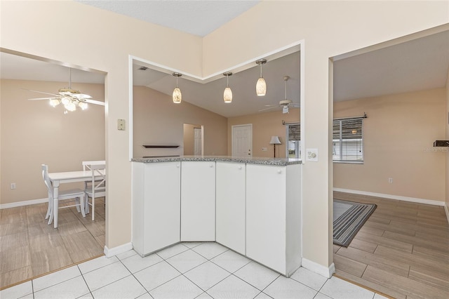 kitchen featuring white cabinetry, ceiling fan, hanging light fixtures, lofted ceiling, and stone countertops