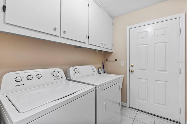 clothes washing area with washer and clothes dryer, light tile patterned flooring, cabinets, and a textured ceiling