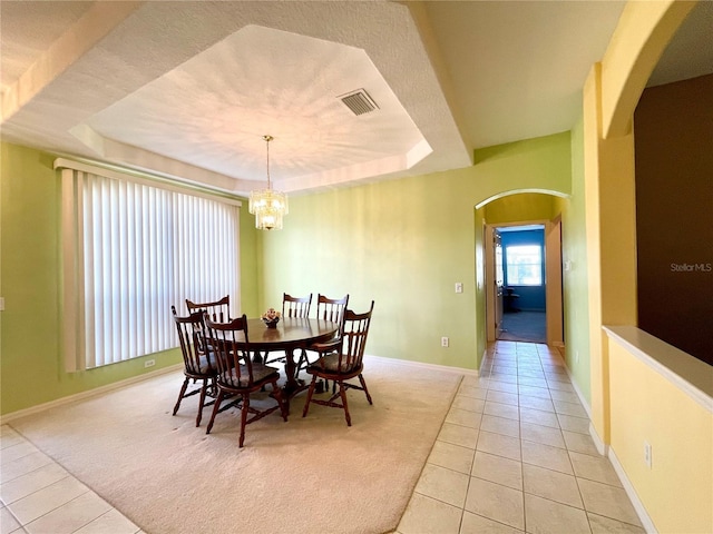 dining area featuring light tile patterned floors, a tray ceiling, and a notable chandelier