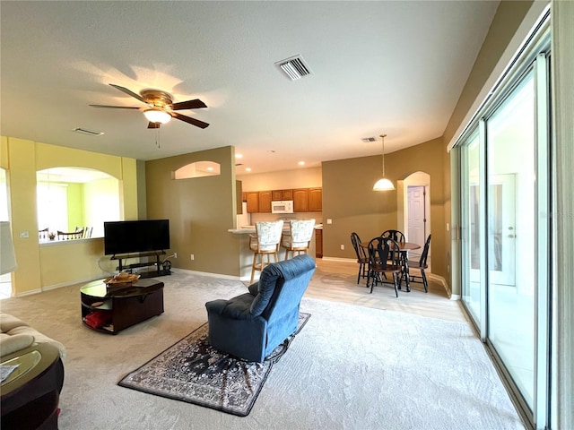 living room with ceiling fan, a healthy amount of sunlight, and light carpet