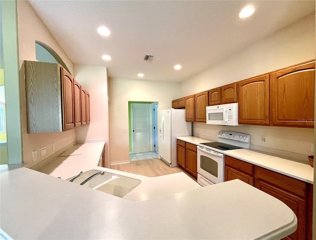 kitchen featuring kitchen peninsula, white appliances, light hardwood / wood-style flooring, and sink