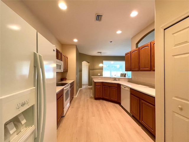 kitchen with light hardwood / wood-style flooring, hanging light fixtures, and white appliances