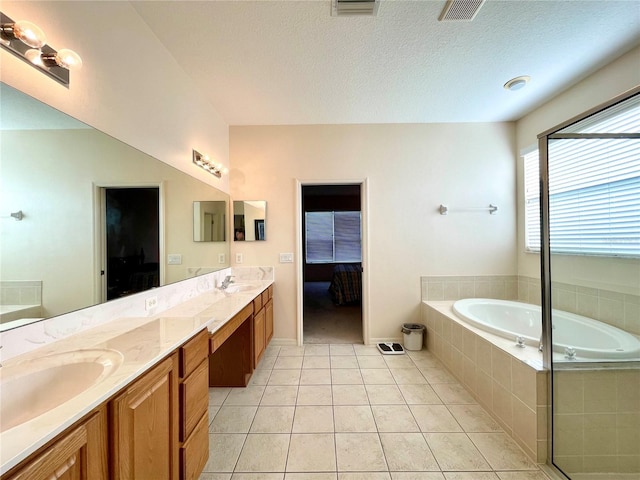 bathroom featuring tile patterned floors, a relaxing tiled tub, a textured ceiling, and vanity