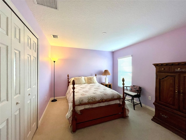 carpeted bedroom with a textured ceiling and a closet