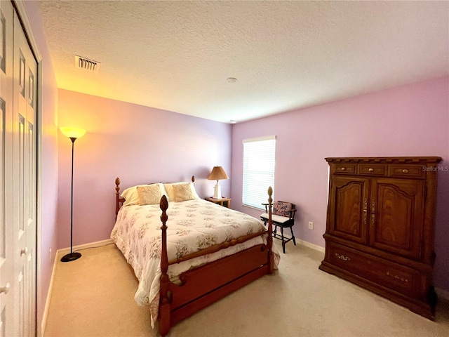 bedroom with a textured ceiling and light colored carpet