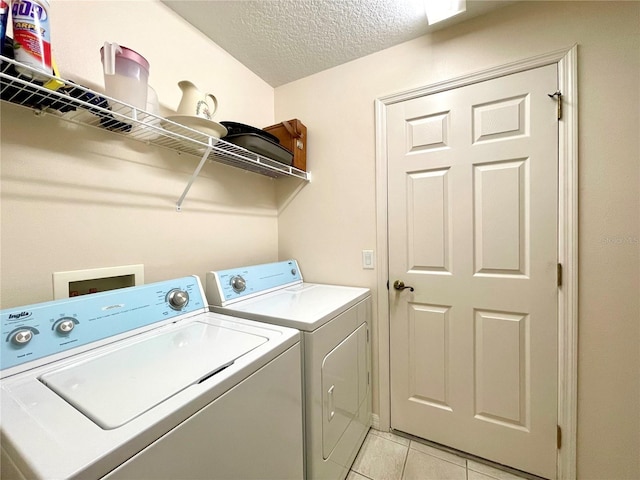 clothes washing area with light tile patterned floors, a textured ceiling, and washing machine and clothes dryer