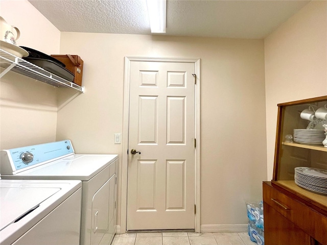 laundry area featuring independent washer and dryer, a textured ceiling, and light tile patterned floors