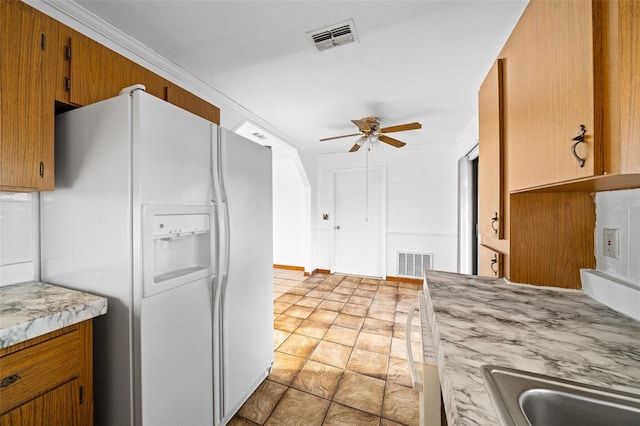 kitchen featuring white fridge with ice dispenser, crown molding, and ceiling fan