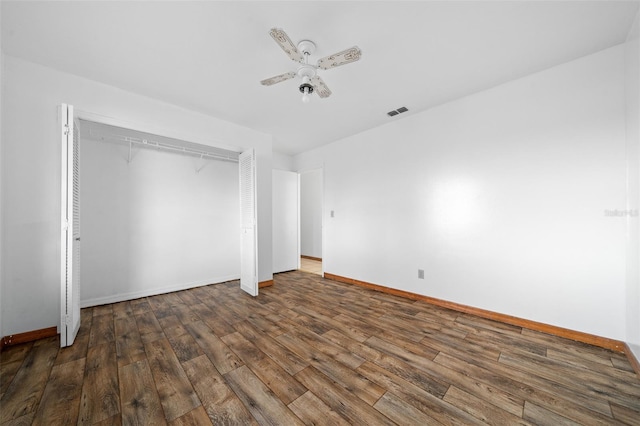 unfurnished bedroom with dark hardwood / wood-style flooring, ceiling fan, and a closet