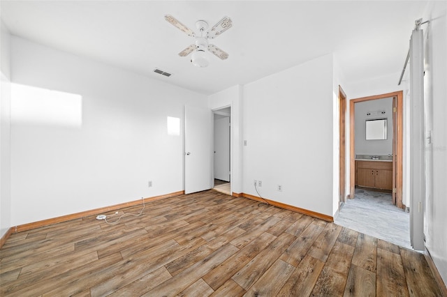 unfurnished bedroom featuring ensuite bathroom, ceiling fan, and light wood-type flooring