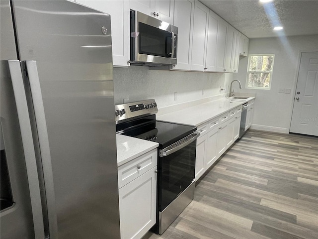 383 S Rooks Ave, Inverness, FL 34453 - kitchen with light wood finished floors, a sink, stainless steel appliances, light countertops, and white cabinetry