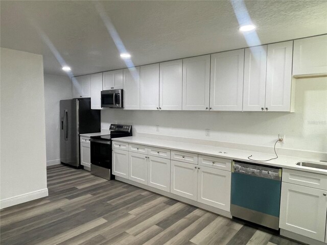383 S Rooks Ave, Inverness, FL 34453 - kitchen featuring dark wood-type flooring, baseboards, light countertops, appliances with stainless steel finishes, and white cabinetry