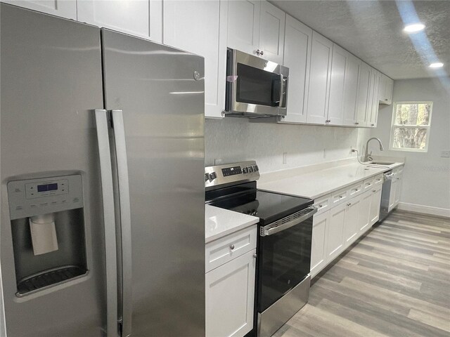 383 S Rooks Ave, Inverness, FL 34453 - kitchen with light countertops, light wood-style flooring, white cabinets, stainless steel appliances, and a sink
