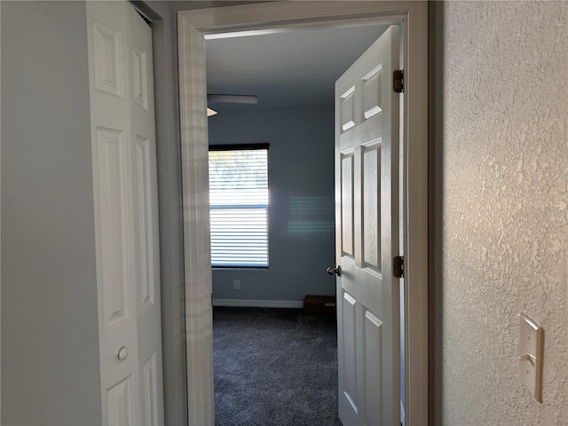 hall featuring dark colored carpet