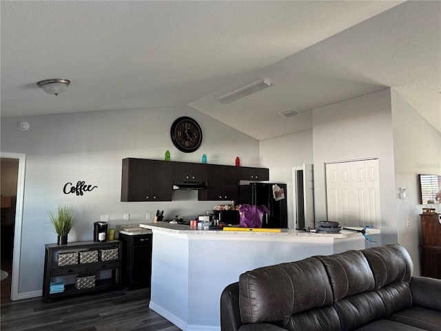 kitchen with kitchen peninsula, black refrigerator, lofted ceiling, and dark wood-type flooring