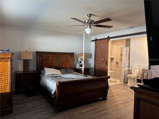 bedroom featuring hardwood / wood-style flooring, ceiling fan, a barn door, and connected bathroom