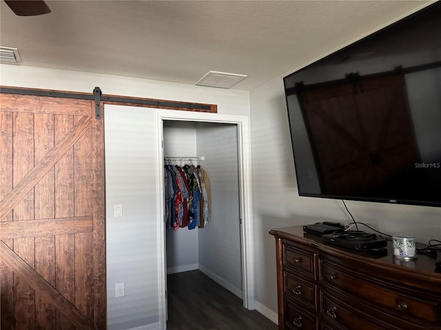 bedroom featuring dark hardwood / wood-style flooring, a barn door, and a closet