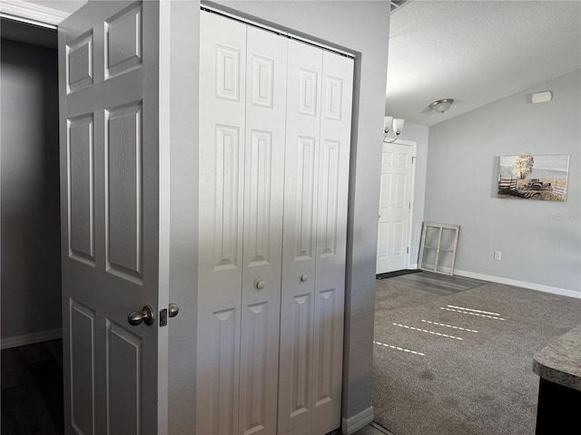 corridor featuring dark carpet and lofted ceiling