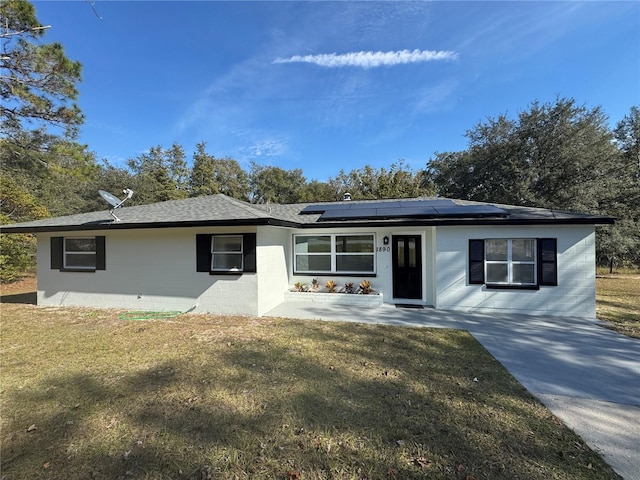 ranch-style house with concrete block siding, roof with shingles, and a front lawn