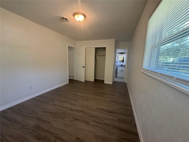 unfurnished bedroom featuring a textured ceiling, a closet, and dark hardwood / wood-style floors