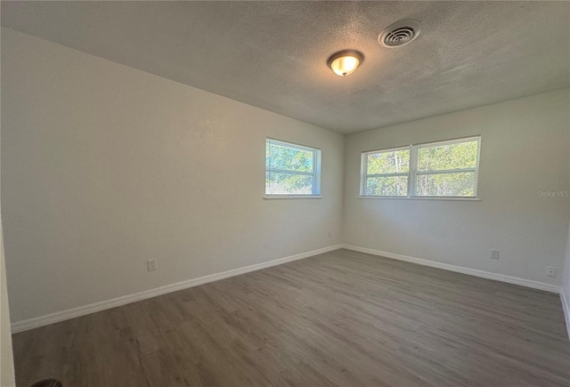 spare room featuring dark hardwood / wood-style floors and a textured ceiling