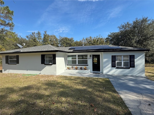 single story home with a front lawn, a patio area, and concrete block siding