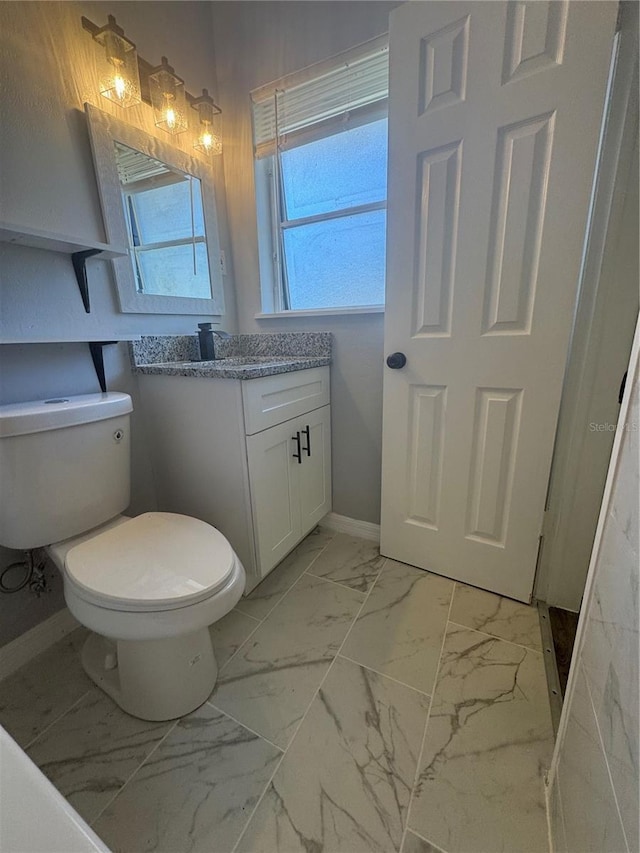 bathroom featuring toilet, marble finish floor, baseboards, and vanity