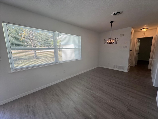 spare room featuring wood finished floors, visible vents, and baseboards