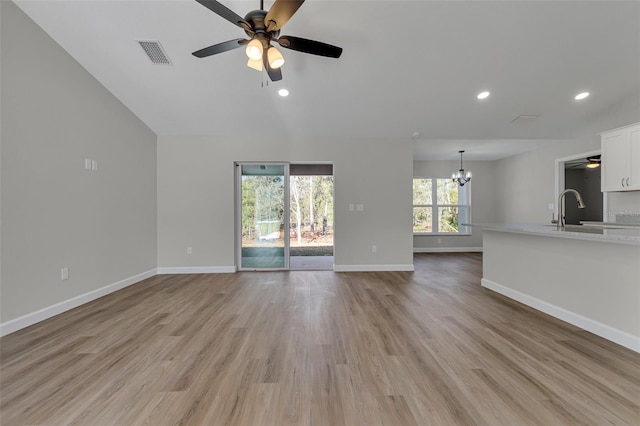 unfurnished living room with light hardwood / wood-style flooring, ceiling fan with notable chandelier, and sink