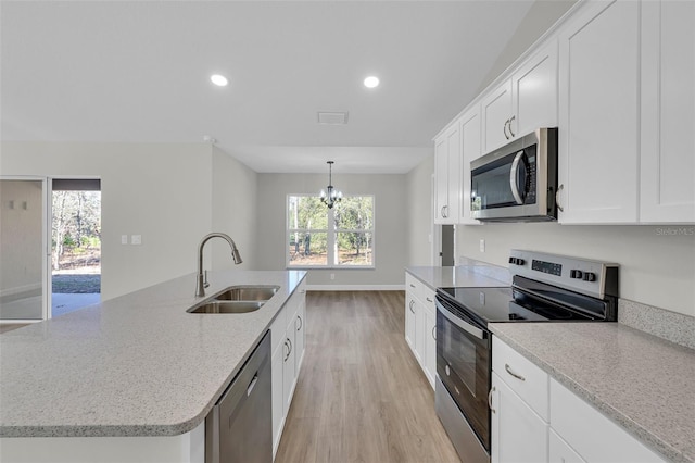 kitchen featuring an inviting chandelier, a center island with sink, white cabinets, sink, and stainless steel appliances