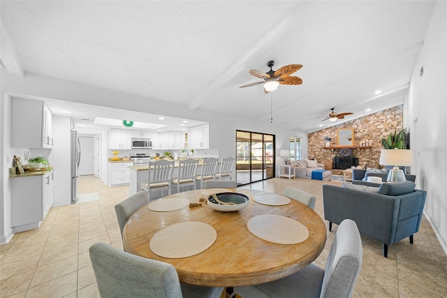 dining space with beam ceiling, light tile patterned floors, a fireplace, and ceiling fan