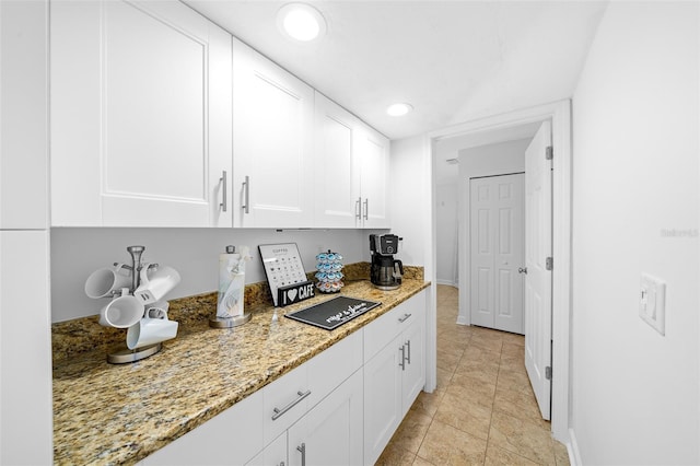 kitchen featuring light tile patterned flooring, white cabinets, and light stone counters