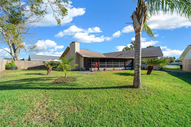 back of property with a sunroom and a lawn