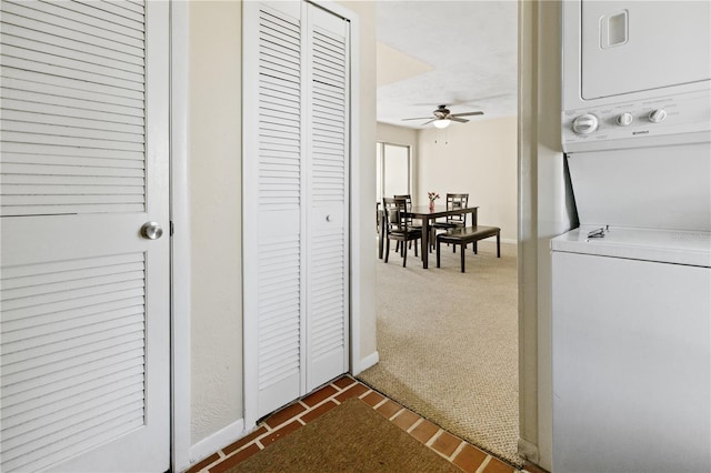 corridor with dark carpet and stacked washer / drying machine