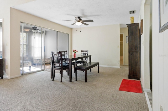 dining area featuring ceiling fan and light carpet