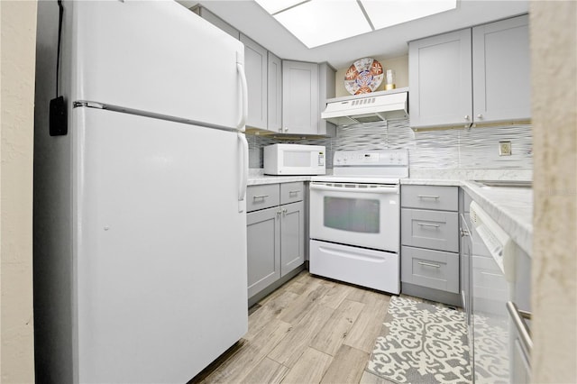 kitchen with custom range hood, white appliances, tasteful backsplash, and gray cabinetry