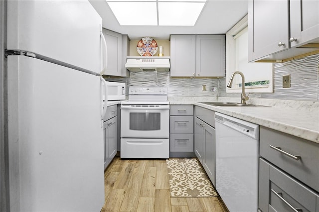 kitchen featuring gray cabinetry, sink, backsplash, white appliances, and light wood-type flooring