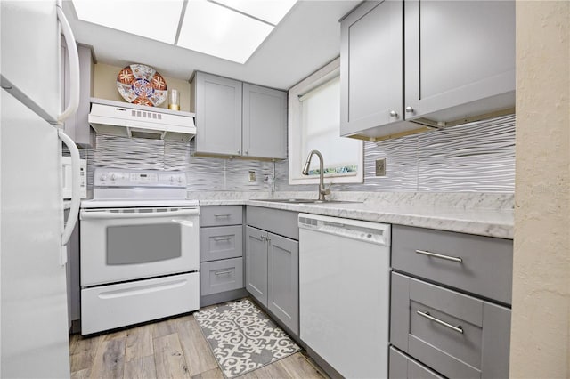 kitchen featuring gray cabinetry, white appliances, ventilation hood, sink, and light hardwood / wood-style flooring