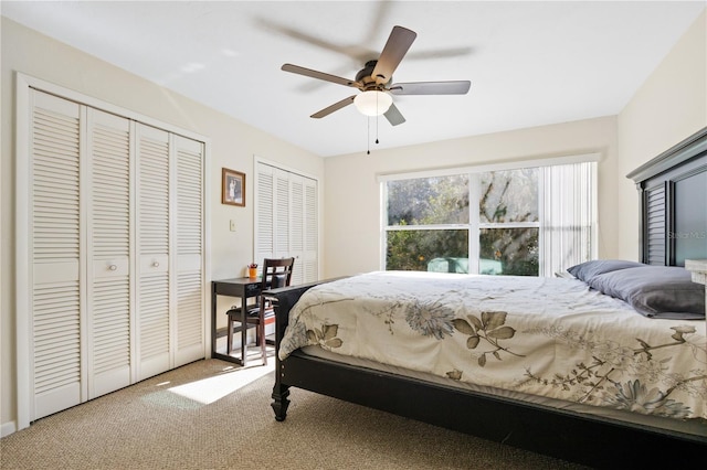 carpeted bedroom with ceiling fan and two closets