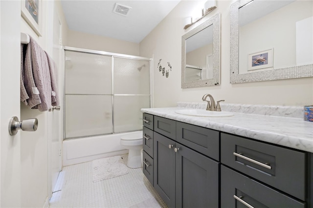 full bathroom featuring toilet, vanity, tile patterned floors, and bath / shower combo with glass door