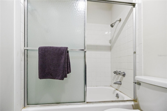 bathroom featuring toilet and bath / shower combo with glass door