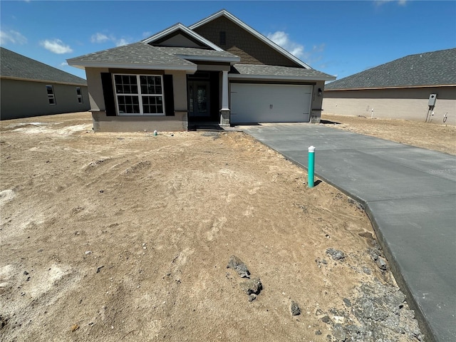 view of front facade featuring an attached garage, roof with shingles, concrete driveway, and stucco siding