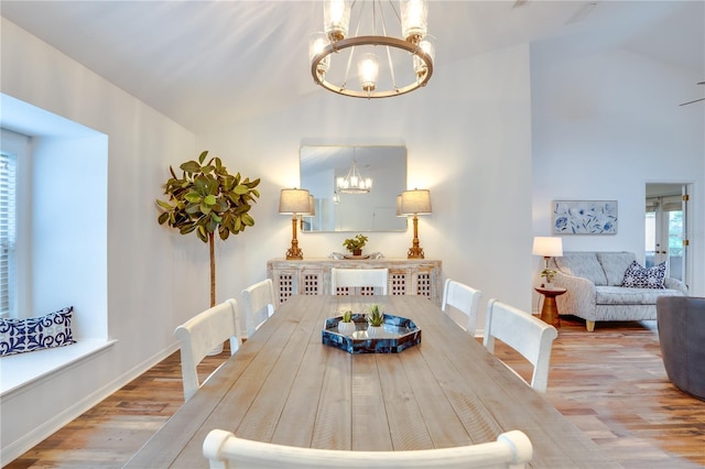 dining room featuring hardwood / wood-style floors, vaulted ceiling, and an inviting chandelier